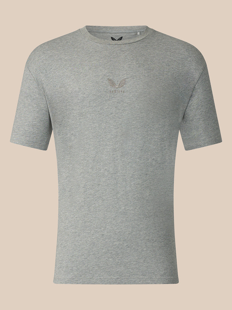 A heather gray short-sleeve crewneck t-shirt with a small tonal embroidered eagle logo and the word 'CASTORE' on the center chest, displayed against a solid light beige background.