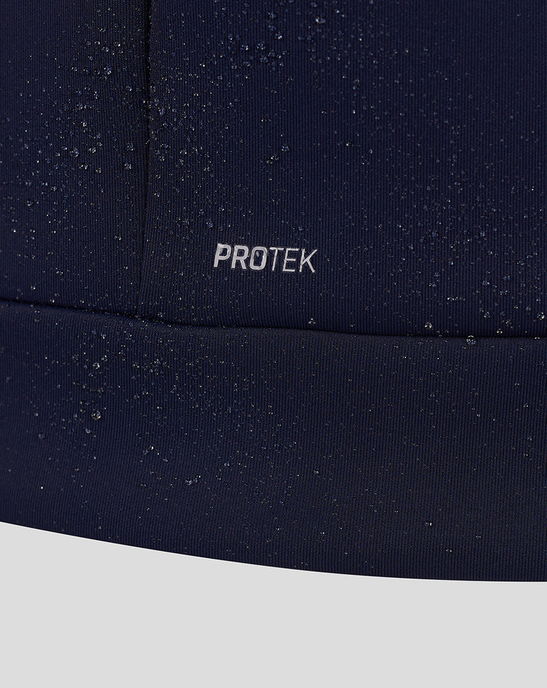 Close-up of navy fabric with PROTEK branding and scattered water droplets.