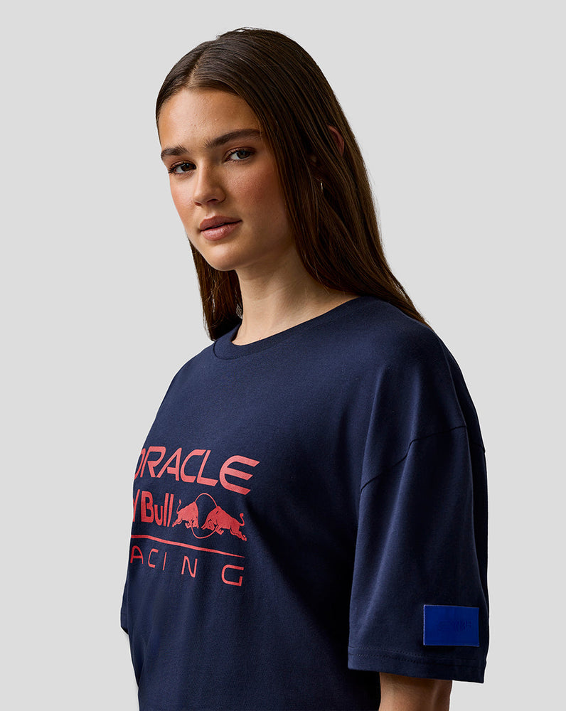 Person wearing a navy blue t-shirt with red and white text and logo on a light gray background